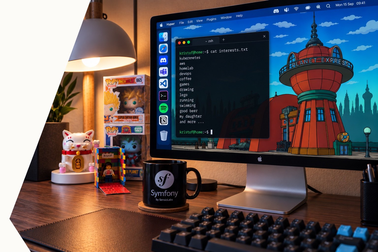 Kristof's desk: a monitor with a terminal listing his interests, a Symfony mug and a lucky cat figurine.